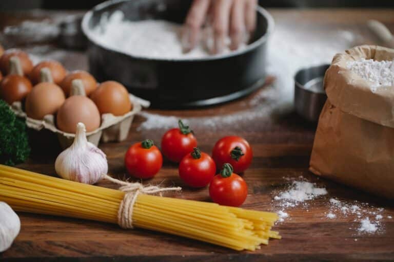 Fresh ingredients including eggs, garlic, tomatoes, and pasta