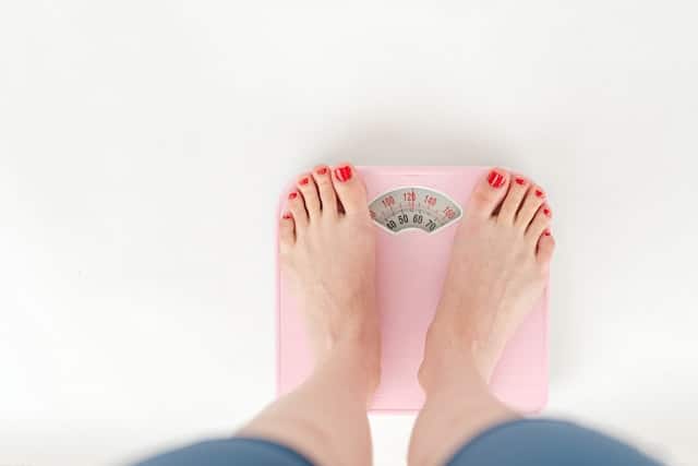 A woman weighs herself on a scale